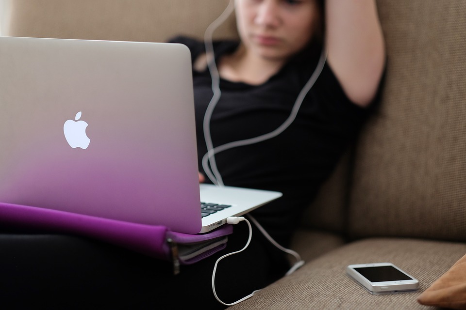 girl working on an apple laptop on her couch